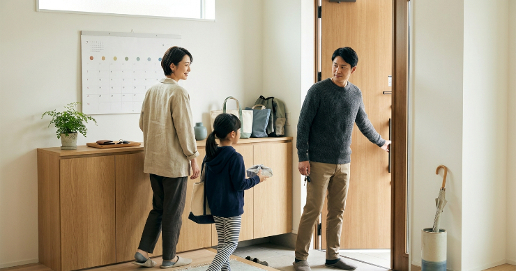 玄関でカレンダーを確認して忘れ物なく外出する日本人家族